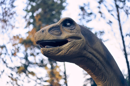 Against the background of trees is the head of a brachiosaurus, one of the largest and most popular. He lived at the end of the Jurassic period. There is a place to copy. High quality photoの写真素材
