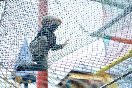 A boy is playing in a childrens maze, jumping on a grid. Hobbies and entertainment. Happy child, happy childhood. The concept of summer holidays. High quality photoの写真素材