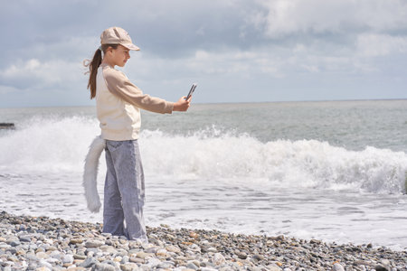 A quadrobra girl takes a selfie by the sea. The concept of entertainment where children dress up as...