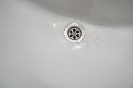 View of a metal drain in a white ceramic bathroom sink. With space to copy. High quality photoの写真素材