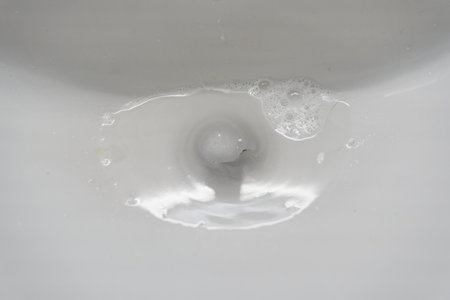 White ceramic bathroom sink with water that goes down the drain. With space to copy. High quality photoの写真素材