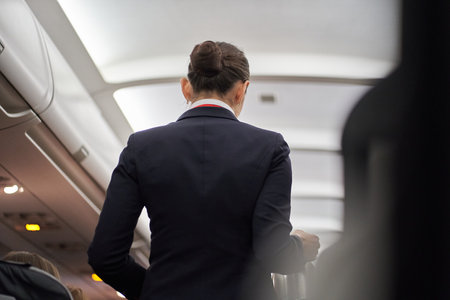 An unrecognizable flight attendant serves hot drinks on board the plane. View of the ceiling in the hallway of the plane. High quality photoの写真素材
