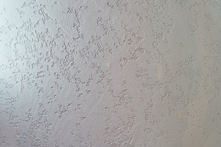Uneven background with the texture of decorative plaster painted in white concrete wall. Rough wall with space for copying. High quality photoの写真素材