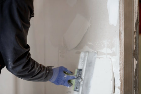 The workers hands putty the wall with a spatula. Apartment renovation. Sealing openings between drywall. With space to copy. High quality photoの写真素材