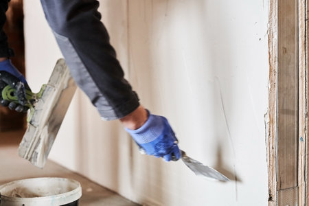A metal spatula lines the wall with plaster. Apartment renovation. Leveling the plastered wall. With space to copy. High quality photoの写真素材