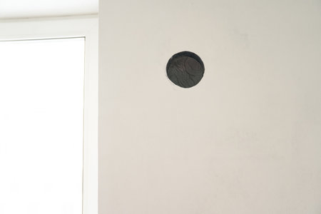 A light-colored wall with an opening for ventilation against the background of a window. With space to copy.の写真素材