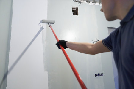 A man paints the inner wall of his house. Apartment renovation. Concrete walls are painted with a paint roller. High quality photoの写真素材