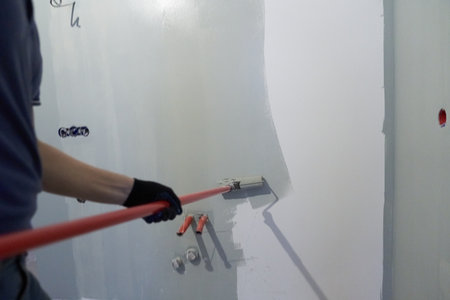A man paints the inner wall of his house. Apartment renovation. Concrete walls are painted with a paint roller. High quality photoの写真素材