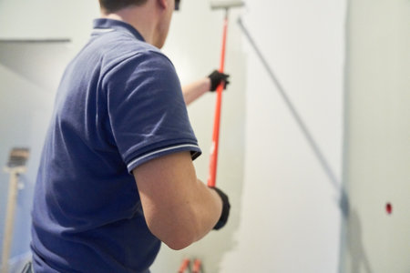 Mens hands paint walls with a roller, work painting on the surface, painting walls in an apartment, repair with white paint. With space to copy. High quality photoの写真素材