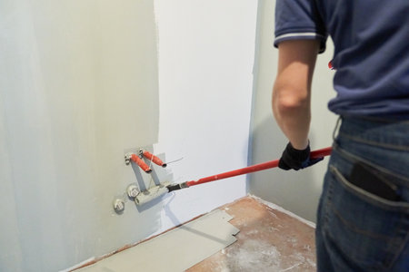A man paints the inner wall of his house. Apartment renovation. Concrete walls are painted with a paint roller. High quality photoの写真素材