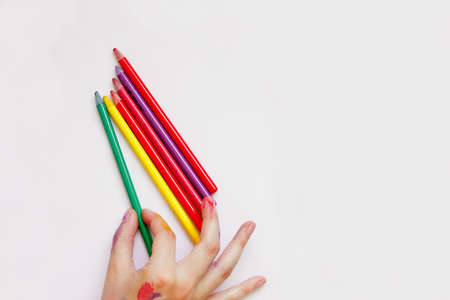 The girl takes a green crayon for drawing with her fingers. White backgroundの写真素材
