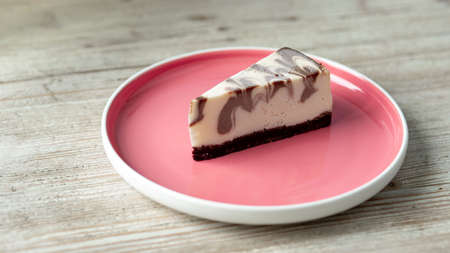 mixed chocolate frozen cheesecake on a pink plate on a wooden tableの写真素材