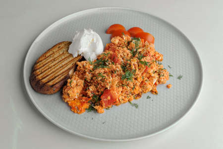 Omelet with tomatoes, cheese and a sandwich on a white plate on a white backgroundの写真素材