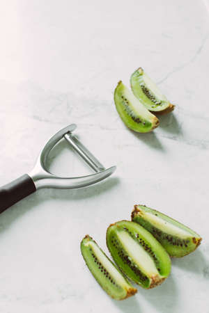 sliced kiwi on a light background and a special knife for peelingの写真素材