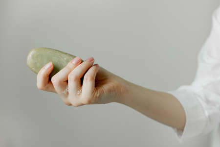 Girl holds a bar of soap in hand on a white background
