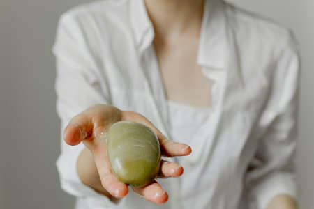 Girl holds a bar of soap in hand on a white backgroundの写真素材