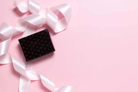 Small gift box and pink ribbon for gift wrapping on pink backgroundの写真素材