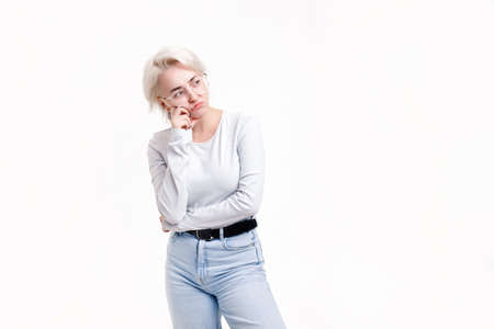 Young blonde girl on a white background indignantly looks to the side, close-upの写真素材