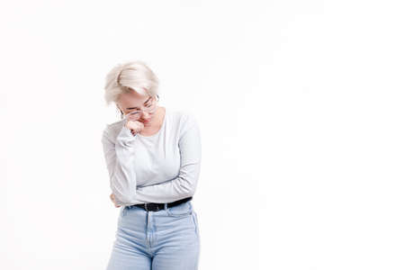 Young blonde girl on a white background indignantly looks to the side, close-upの写真素材
