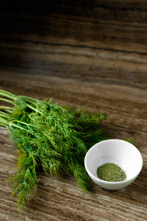 Fresh and dried dill on a wooden board