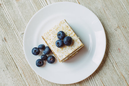 Honey cake with blueberries in a white saucer on the tableの写真素材