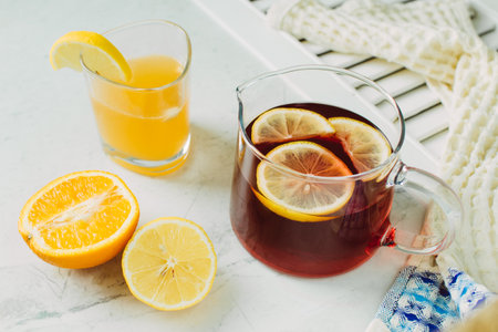 Pitcher of fresh lemon iced tea with filled glass on a rustic white backgroundの写真素材