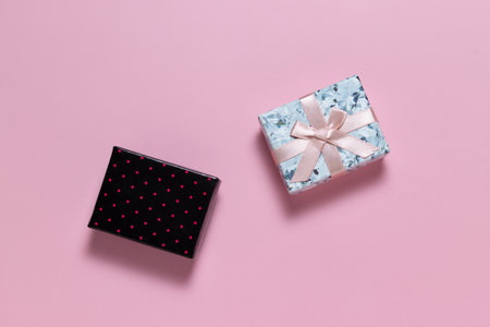 Small gift boxes light with a bow, and dark with pink polka dots on a pink backgroundの写真素材