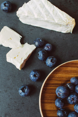 Camembert cheese with blueberries on dark background, side view. Food for wine.の写真素材