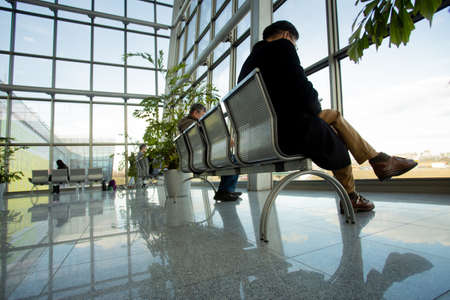 People sit on a bench in a glass office building and waitの写真素材