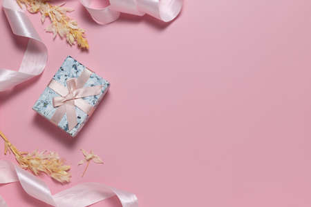 Small gift box with bow and pink ribbon for gift wrapping on pink backgroundの写真素材