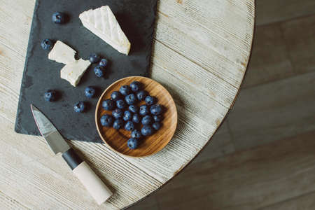 Brie cheese with mold and blueberries on the table