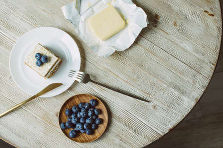 Honey cake with blueberries in a white saucer on the tableの写真素材