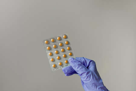 Girl in medical gloves holds pills in hand.