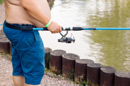 Moscow, July 17, 2021. Full man with a naked torso holding a fishing rod in his hands, fishing in natureのeditorial素材
