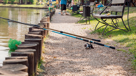 The fishing rod lies on a stone shore and waits for the fish to bite on a sunny summer day in natureの写真素材