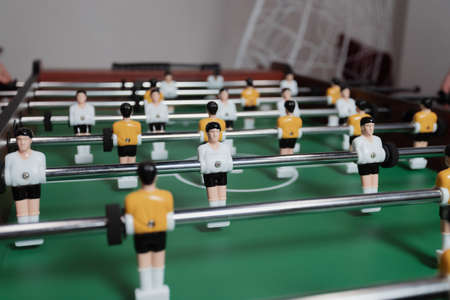 Table soccer. Little toy players in yellow and white uniforms