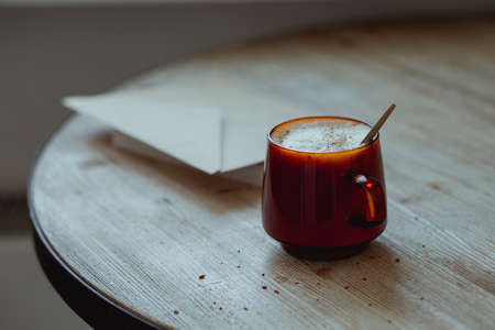 Coffee in a glass cup and morning mail stand on a wooden table.の写真素材