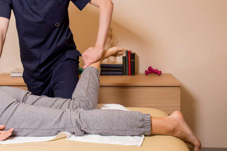 Appointment with an osteopath. The doctor checks the patient, presses on the leg. High quality photoの写真素材