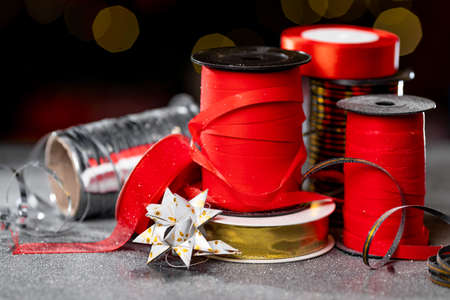 Christmas different ribbon spools for decorating gifts on a dark background with bokeh. High quality photoの写真素材