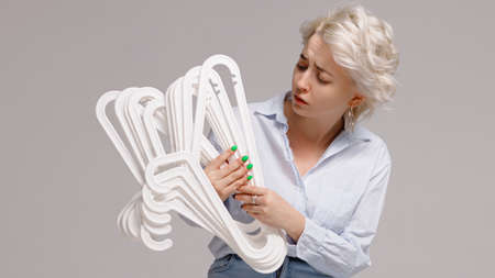 Girl holding a bunch of clothes hangers in her hands on a white background. High quality photoの写真素材