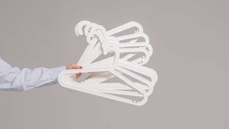 Clothes hangers in the hands of a girl on a light background. High quality photoの写真素材