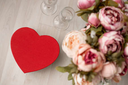 A gift box in the form of a red heart and a bouquet of flowers are on the floor. Valentines Day - February 14th. view from aboveの写真素材