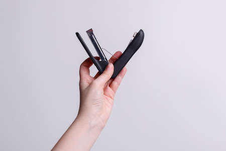 Stapler in the hands of a girl on a white background, stationery. high quality photo