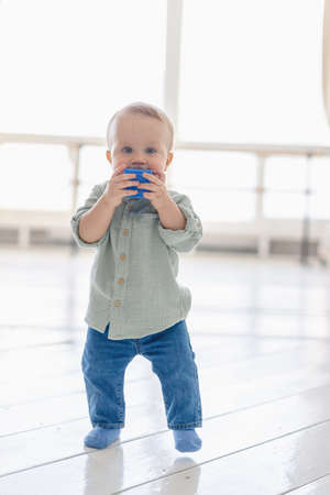 One-year-old baby in jeans and shirt plays with cubes in the apartment. high quality photoの写真素材