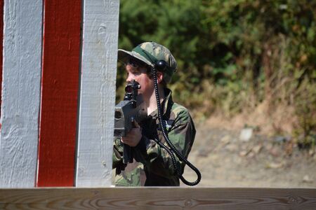 Young Boy playing laser tag while dressed in army style overallsの写真素材