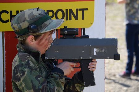 Young Boy playing laser tag while dressed in army style overalls