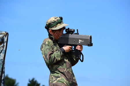 Young Boy playing laser tag while dressed in army style overallsの写真素材