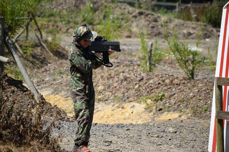 Young Boy playing laser tag while dressed in army style overalls
