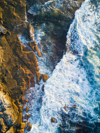 Wave crashing into rock cliff aerial view.の写真素材