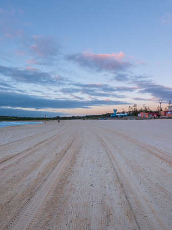 A track of car tyre on empty beach in the morning.の写真素材